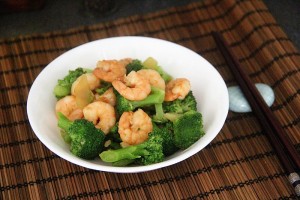 bowl of stir fry king prawn on bamboo placement with chopsticks