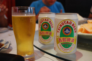 tsintao beer in cans and a glass