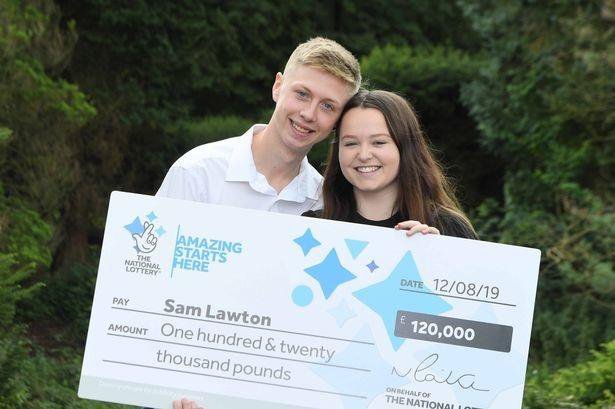 young couple posing for picture with giant cheque after winning lottery