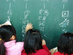 children writing mandarin language characters on chalkboard